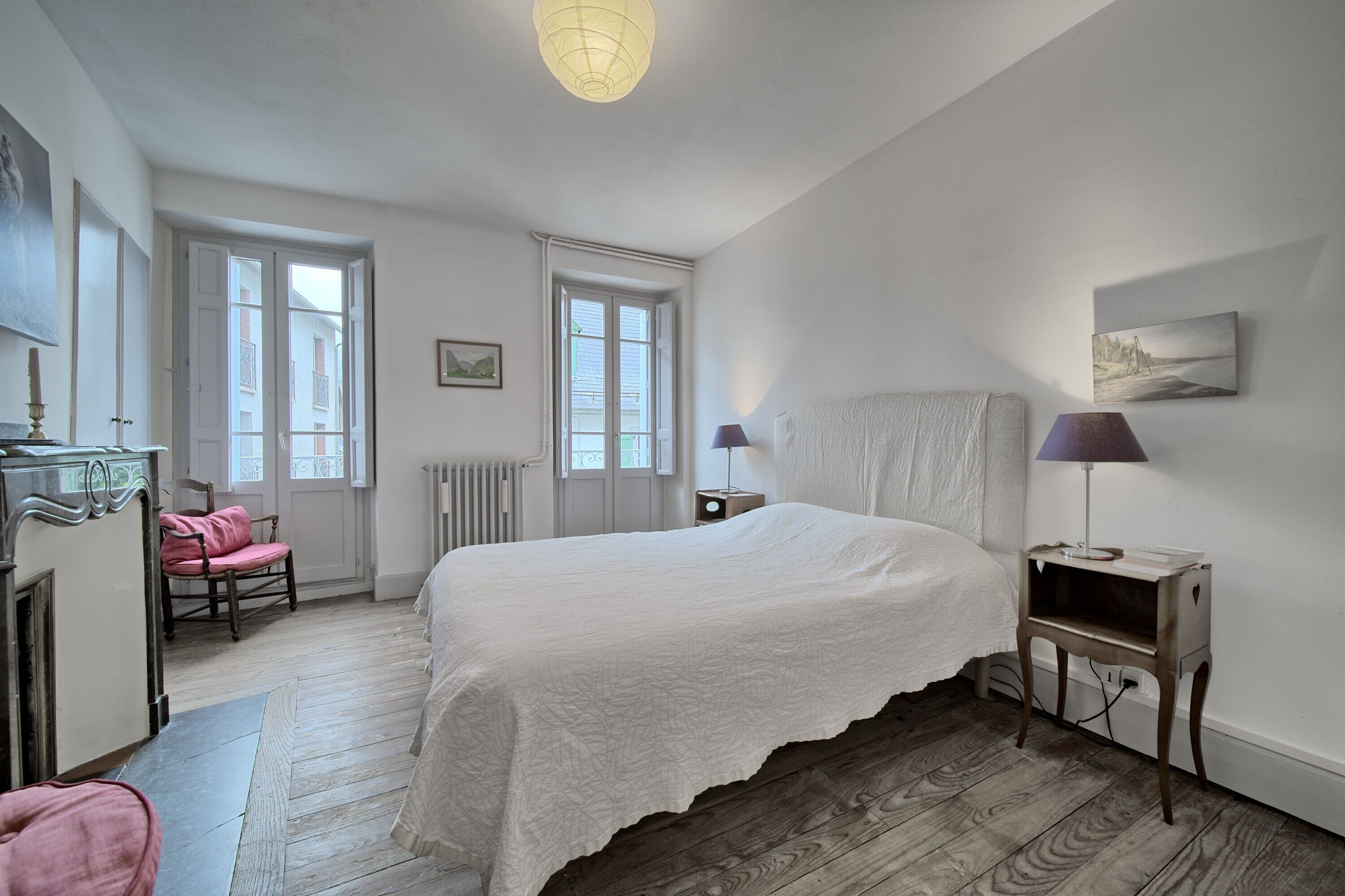 Een slaapkamer met een bed, een stoel, een nachtkastje en een lamp.