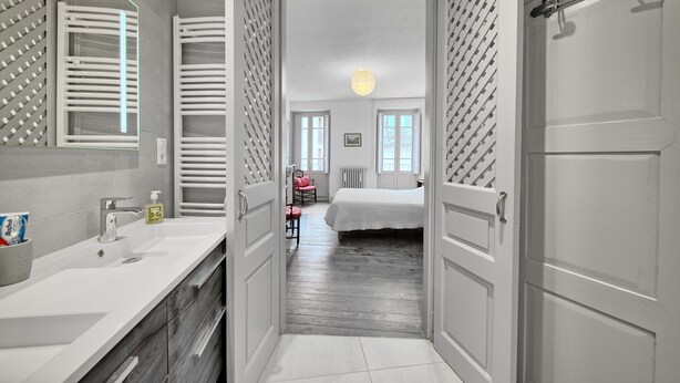 Un baño moderno con lavamanos blanco, espejo y toallero.