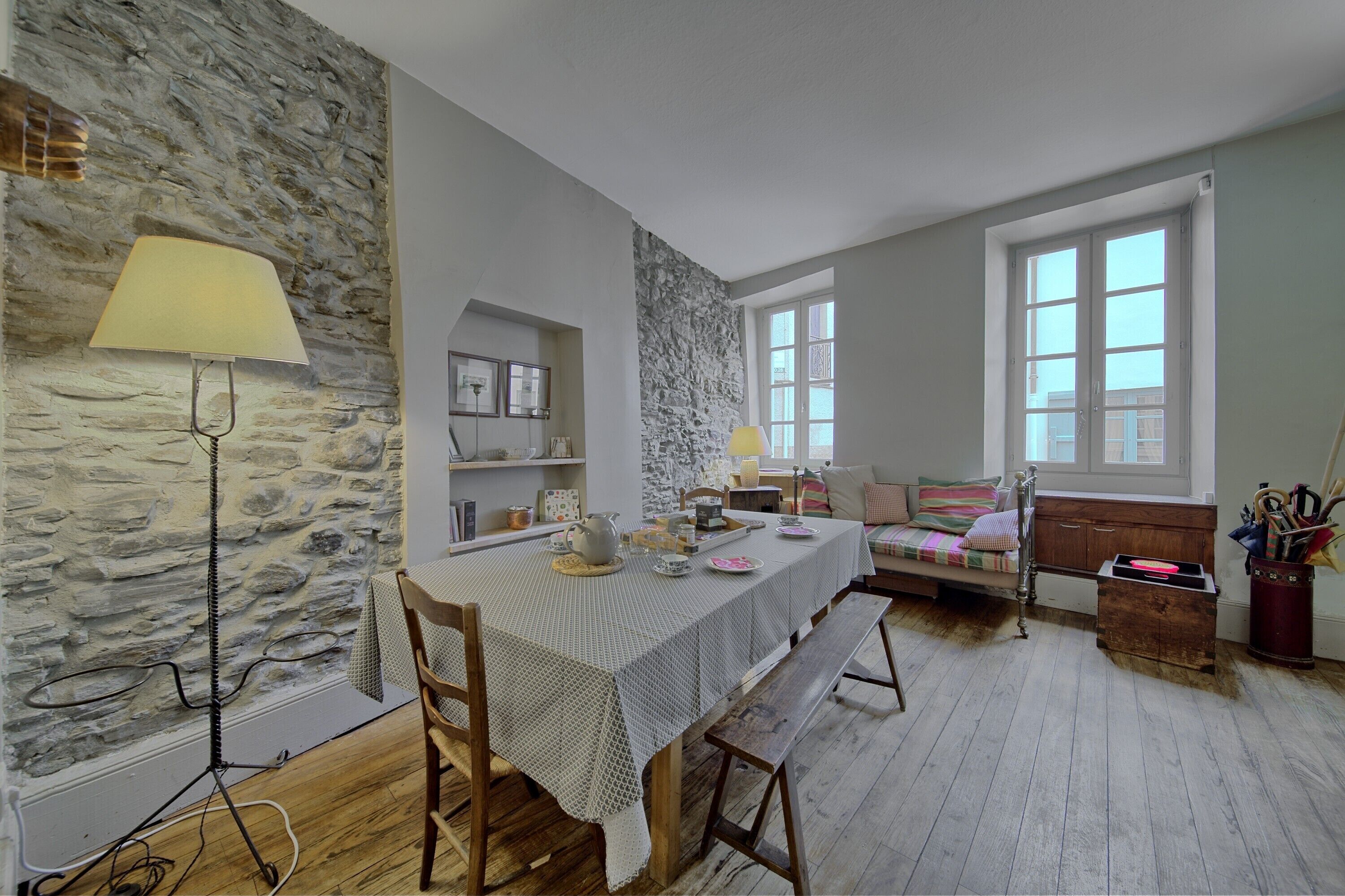 A dining area with a table set for four, a stone wall, and a window with a view.