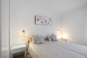 Een slaapkamer met een bed, nachtkastjes, wandlampen en een bloemig kunstwerk aan de muur.
