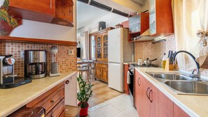 Een keuken met houten kastjes, een koffiezetapparaat, een spoelbak en een plant in een pot.