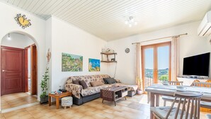 Een woonkamer met een bank, televisie, eettafel en stoelen.