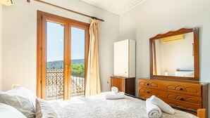 Een hotelkamer met een bed, een dressoir, een spiegel en een balkon met uitzicht.