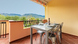 A balcony with a table set for dining, a view of mountains, and a tiled floor. - Apartment 'Dimora Frau' with Shared Pool, Wi-Fi and Air Conditioning (Villasimius)