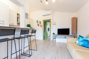 A modern living room with a sofa, TV, and bar area with chairs.