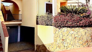 A two-story building with a stone wall, a staircase, and a covered outdoor area. - Apartment 'Dimora Frau' with Shared Pool, Wi-Fi and Air Conditioning (Villasimius)