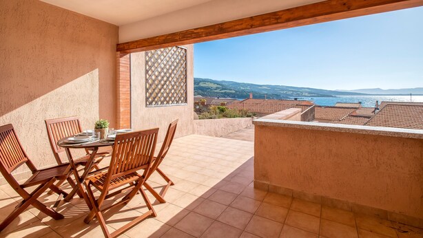A balcony with a table and chairs, a view of the sea, and a distant landscape. - Apartment 'Rosa's' with Sea View and Private Terrace (Isola Rossa)