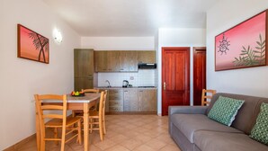 A compact living space with a dining area, kitchenette, and a sofa. - Apartment 'Rosa's' with Sea View and Private Terrace (Isola Rossa)