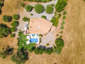 Vue aérienne d’une propriété dotée d’une piscine, d’un patio couvert et d’un espace verdoyant.