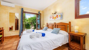 A hotel room with two beds, a wooden headboard, a nightstand, a mirror, and a view of the outdoors.