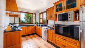 A kitchen with wooden cabinets, stainless steel appliances, and a window with a view.