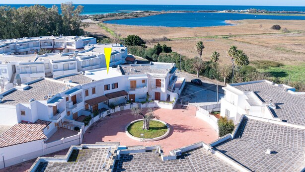 Eine Küstenwohngegend mit weißen Gebäuden, einem zentralen Innenhof und Blick auf das Meer.