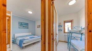 Ein Schlafzimmer mit einem Bett, Etagenbetten, einem Fenster und einer Tür.