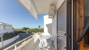 Ein Balkon mit Tisch und Stühlen, Blick auf die Straße und ein Gebäude im Hintergrund.