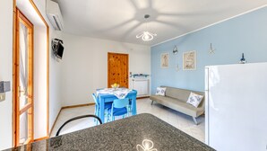Eine kleine Küche mit einer Granit-Arbeitsplatte, einem Esstisch mit Stühlen, einer Couch und einem Kühlschrank.