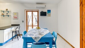 Ein Essbereich mit Tisch, Stühlen, einem Fenster und einer Küchenzeile.