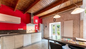 Una cocina moderna con una pared de acento roja, vigas de madera en el techo y un comedor con taburetes de bar.