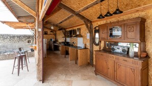 Una cocina rústica con vigas de madera, una barra y vistas a una pared de piedra.