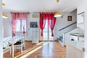 A kitchen with a washing machine, a dining table with chairs, and a staircase leading to an upper level.