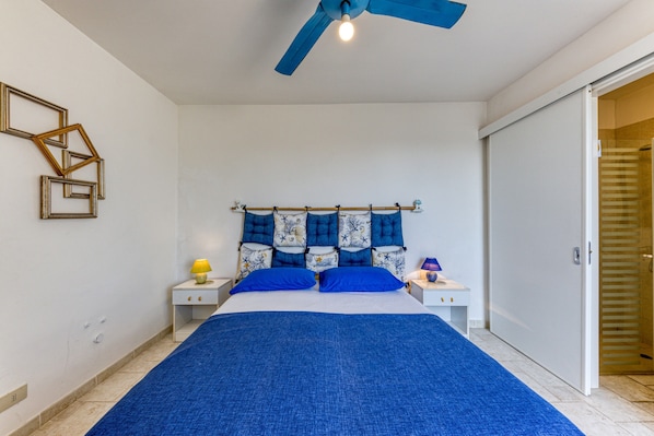 A bedroom with a bed, nightstands, a ceiling fan, and a wardrobe.
