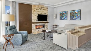 Una sala de estar moderna con chimenea de piedra, un televisor de pantalla plana, un sofá, una mesa de centro y obras de arte en la pared.