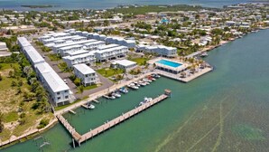 An aerial view of a coastal resort with multiple white buildings, a marina, and a pool area. - Best Catch on Grouper LN at Ocean Isles (Marathon)