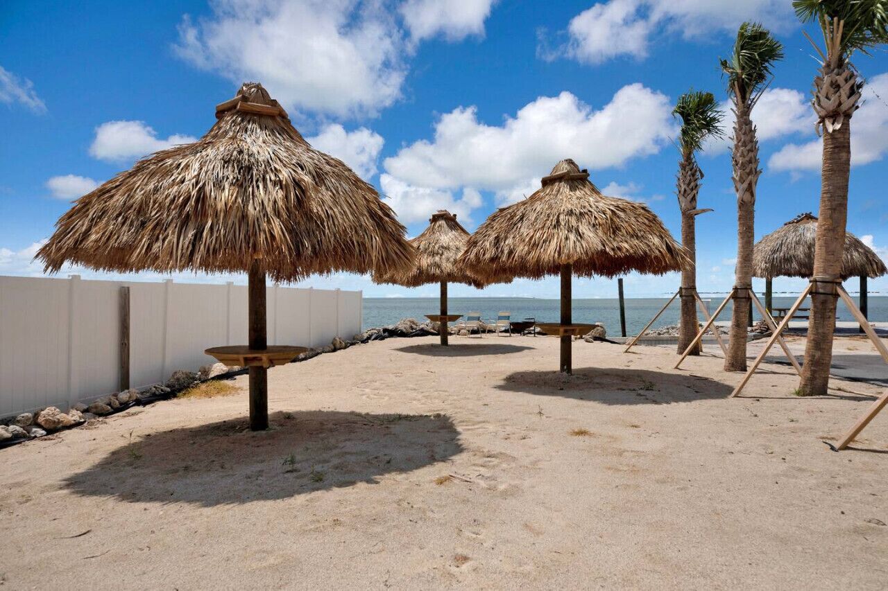 Ein Strand mit Reetdachschirmen und Palmen.