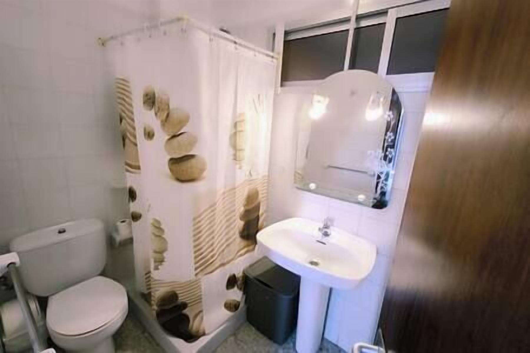 A bathroom with a toilet, a sink, and a shower curtain with a stone pattern.