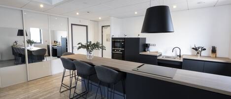 Une cuisine moderne dotée d’un îlot central, de tabourets de bar et d’un luminaire suspendu.