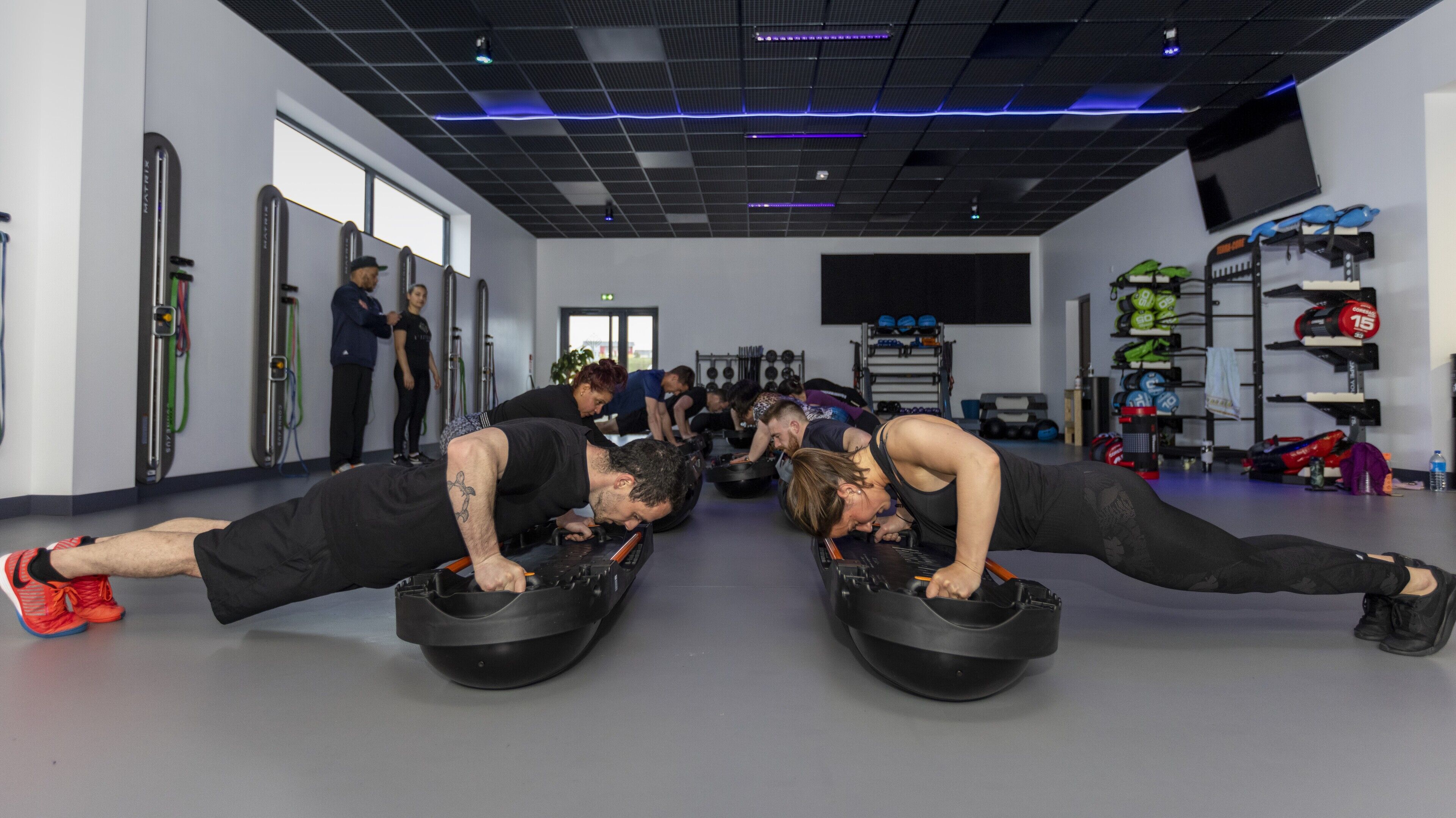 Een sportschool met fitnessapparatuur, waaronder kettlebells en halters.