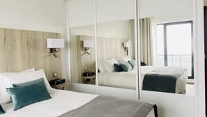 Una moderna camera d'albergo con un letto grande, un comodino, uno specchio e una finestra con tende.