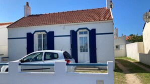 A white building with a red-tiled roof, a car parked in front, and a clear blue sky. - L'océane du pays - Saint hilaire de Riez (SAINT HILAIRE DE RIEZ)