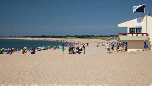 A beach scene with a lifeguard tower, beachgoers, and umbrellas. - L'océane du pays - Saint hilaire de Riez (SAINT HILAIRE DE RIEZ)
