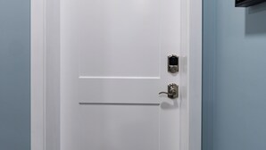 A white door with a numeric keypad lock and a small electronic device on the right side.