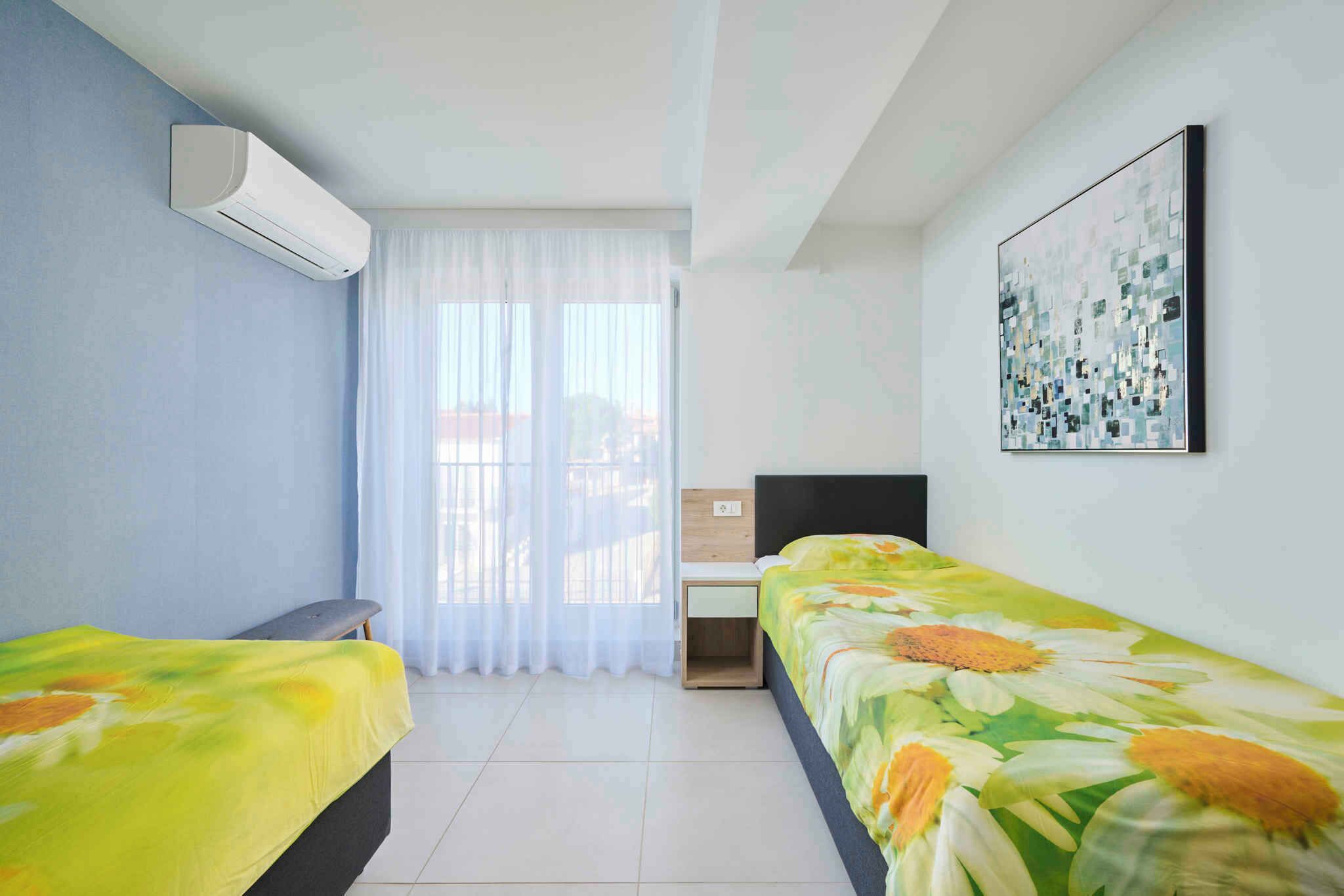 A bedroom with two beds, a window with curtains, a flat-screen TV, and a painting on the wall.