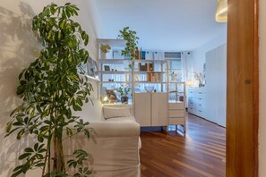 Un salon moderne avec un canapé blanc, une bibliothèque et une grande plante verte.
