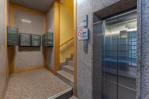 An elevator with a glass door, a no smoking sign, and a fire alarm box. - GuestHost - Bright studio apartment perfect for two people, located in a building with a garden in the Cirenaica district, an area near the center equipped with all services. Located just 20 meters from the entrance to the S.Orsola Polyclinic, it is idea (Bologna)