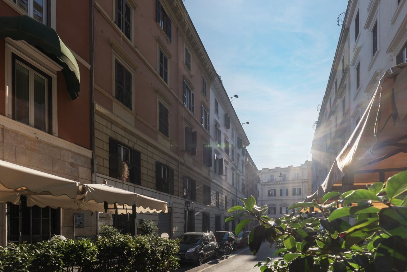 A narrow street with parked cars and buildings on either side.