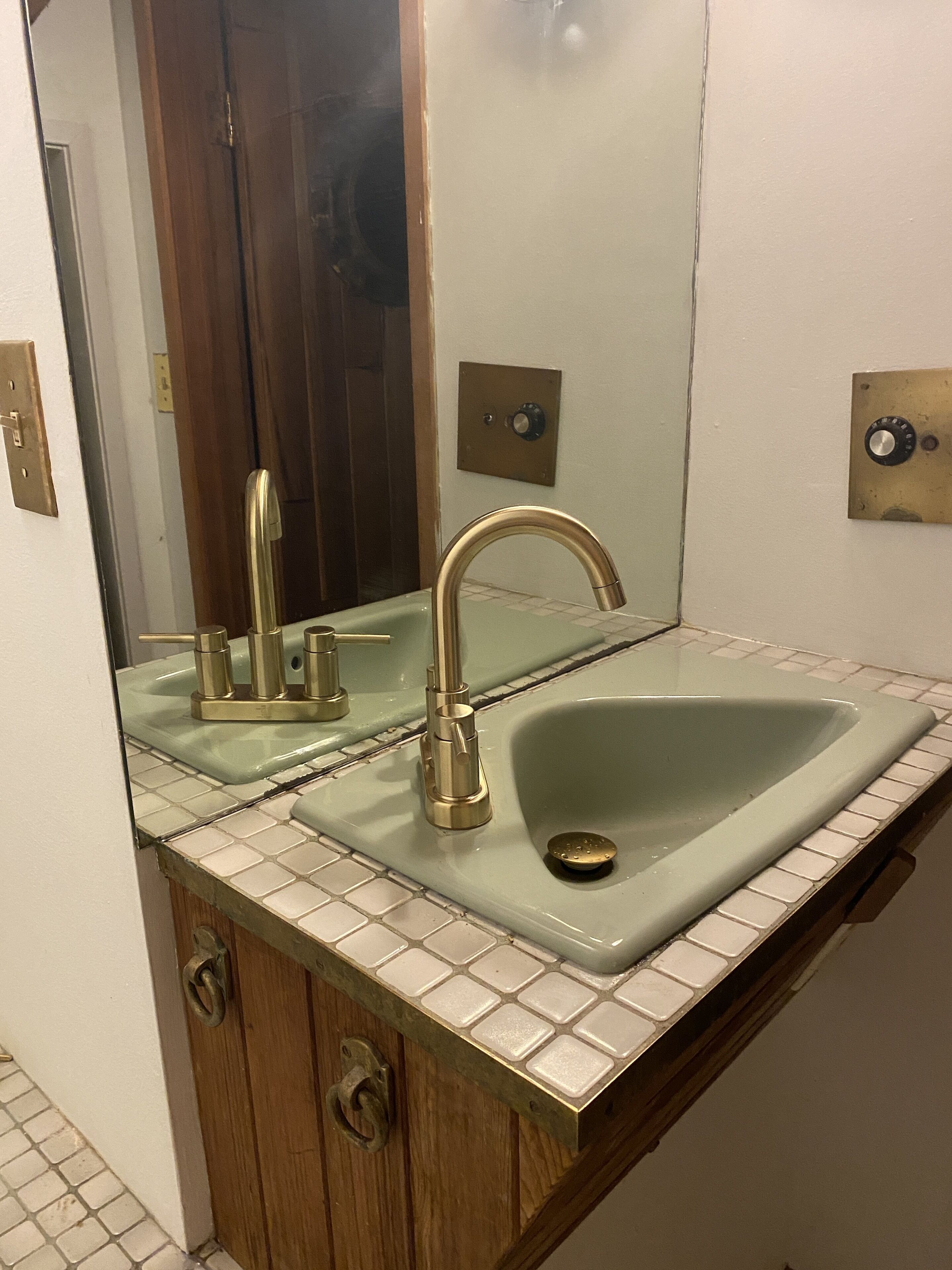 Un baño con lavabo, espejo y mueble de madera.