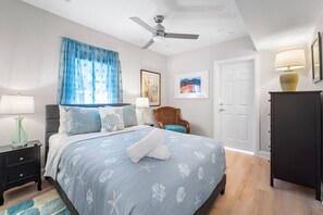 Een slaapkamer met een bed, een stoel, een kledingkast, een plafondventilator en een deur.