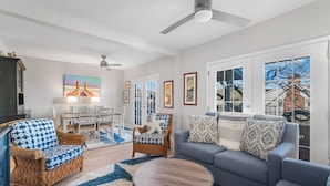 A modern living room with a sofa, armchairs, a coffee table, and a dining set.