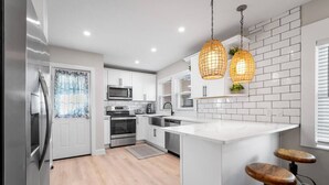 A modern kitchen with white cabinetry, stainless steel appliances, and a central island with stools.