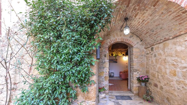 An arched stone entrance with a small step leading into a room. - Stunning apartment in Monticchiello with WiFi (Monticchiello)
