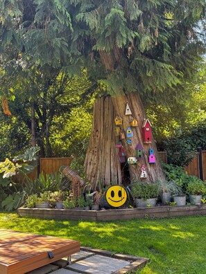 Ein Baum mit bunten Vogelhäusern und einer Smiley-Gesicht-Dekoration.
