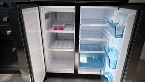 Un réfrigérateur ouvert, doté de plusieurs étagères et de tiroirs, dont certains contiennent des articles.