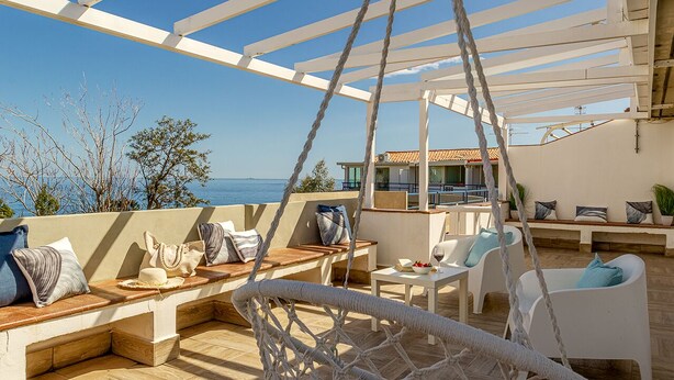 A terrace with a view of the sea, wooden furniture, and a hanging chair. - Sea Sound Loft Naxos (Giardini Naxos)