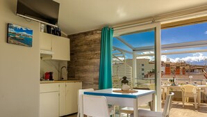 A compact kitchen with a dining area, a view of the city, and a balcony with a table set for two. - Sea Sound Loft Naxos (Giardini Naxos)