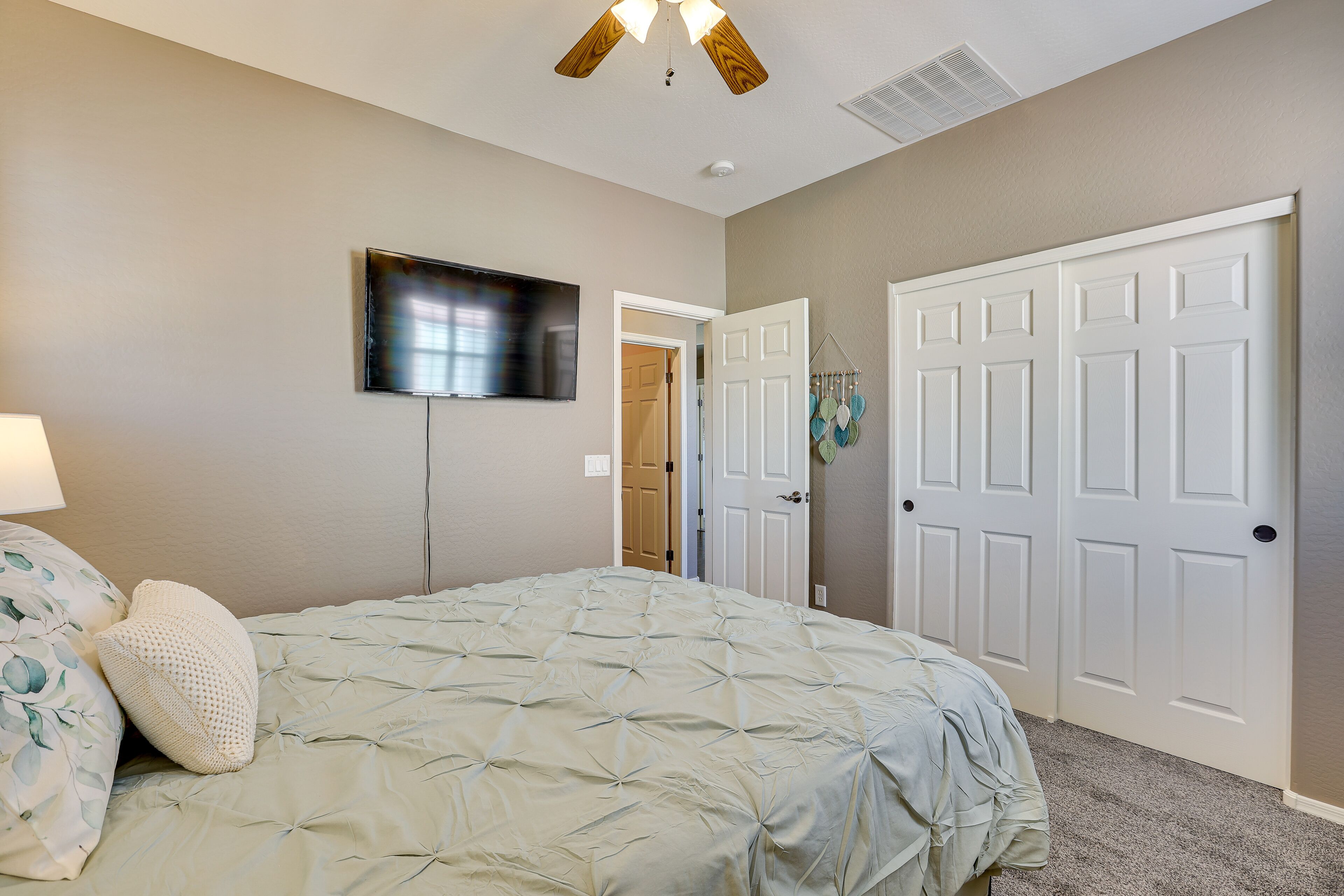 Une chambre à coucher avec un lit, un ventilateur de plafond, une télévision et une porte.