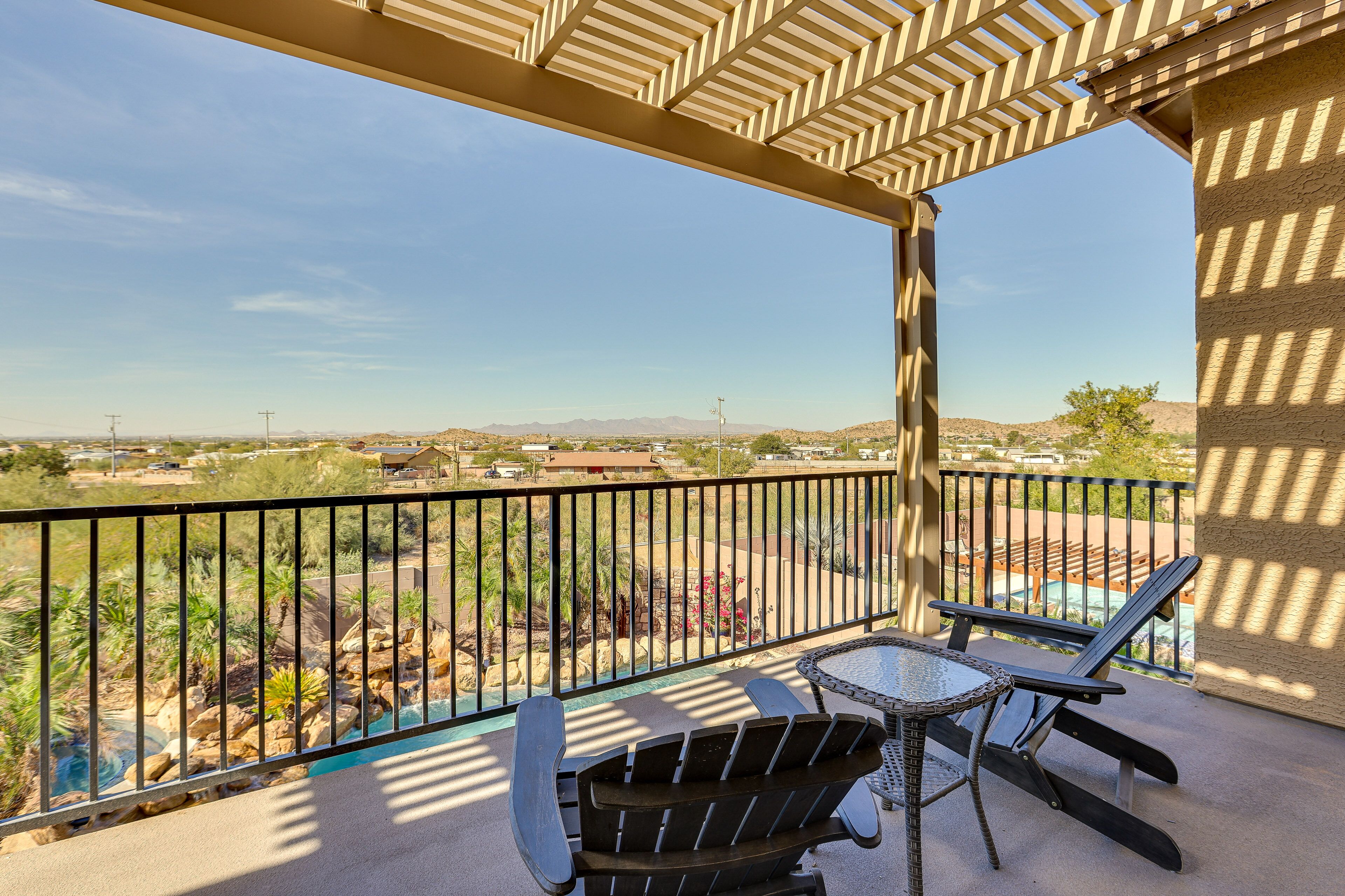 A balcony with a view of a pool and desert landscape.