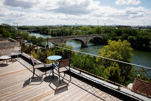 A wooden deck with outdoor furniture overlooking a river and a bridge. - L'Atelier sur Seine (Epinay-sur-Seine)
